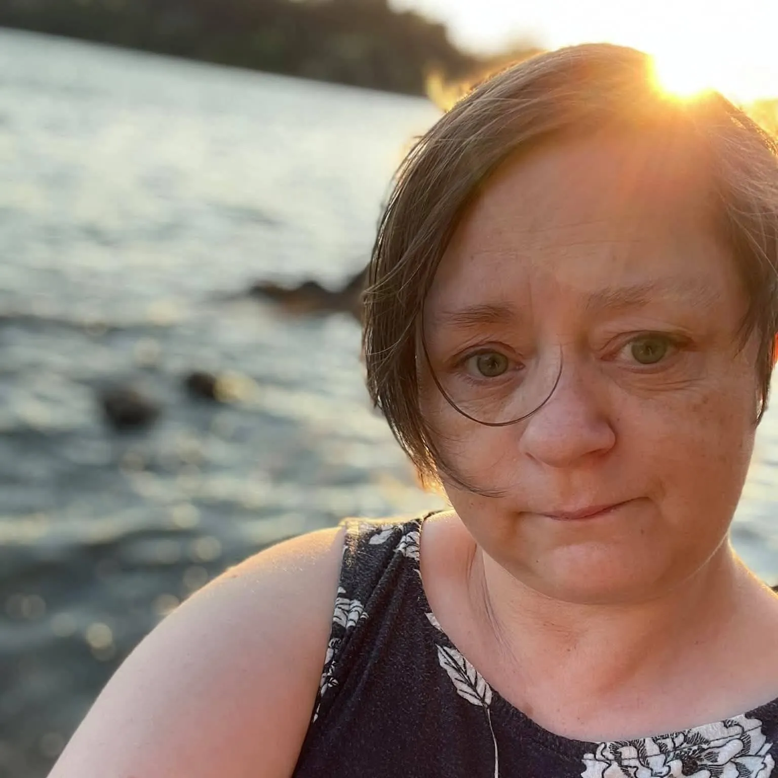 Sarah Gibbins in a close-up portrait by the water.
